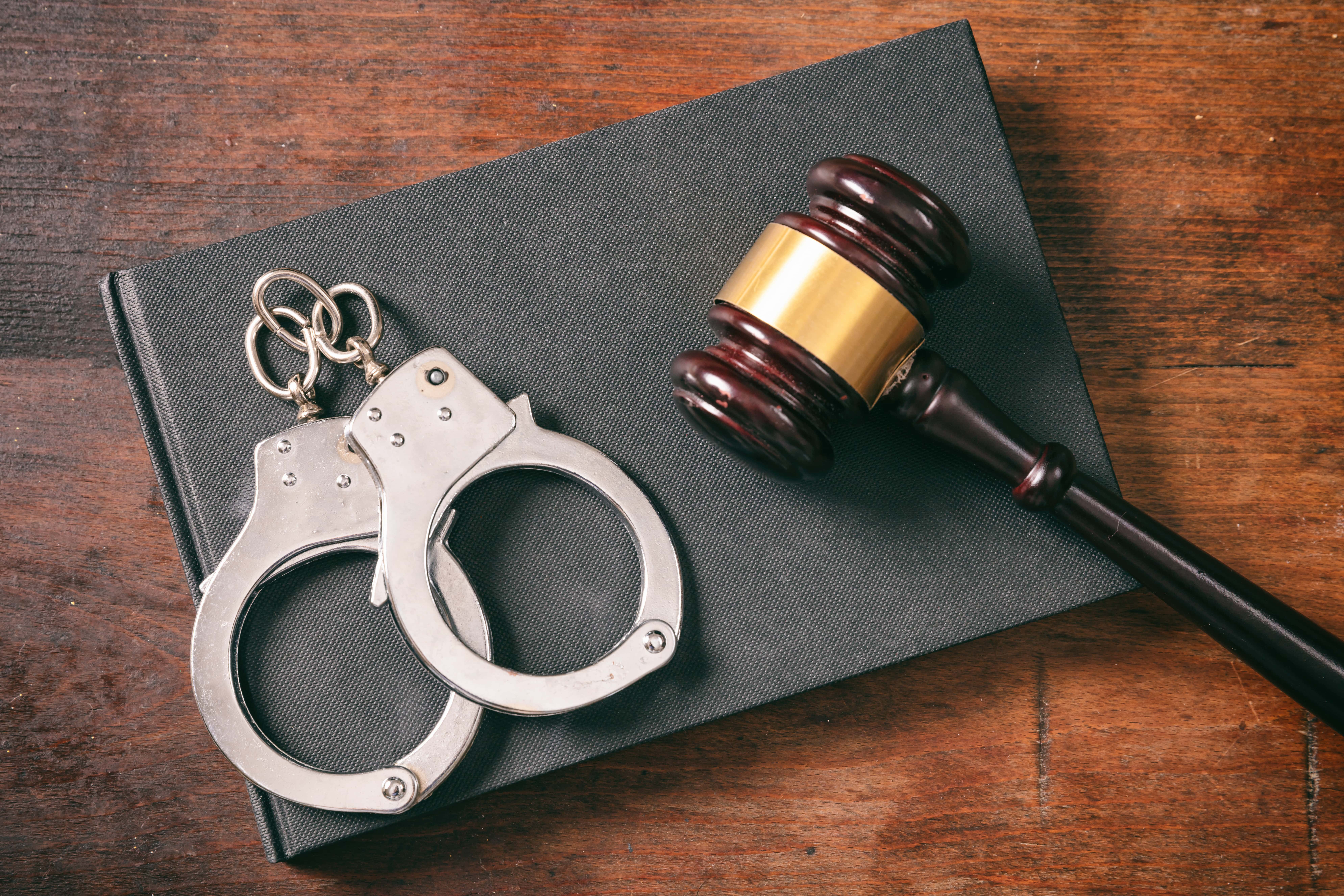 Handcuffs, gavel on book on a wooden background