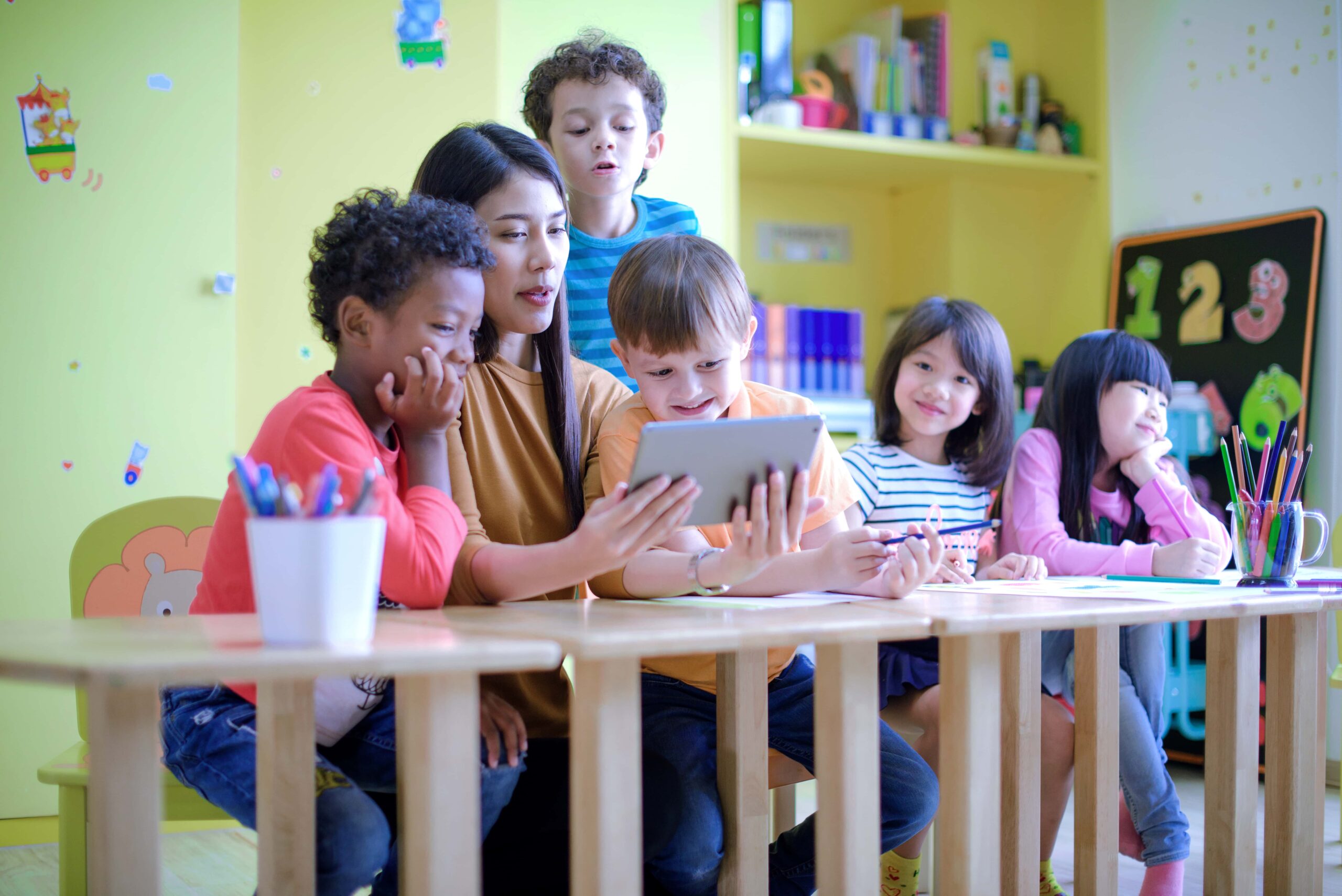 Kindergarten teacher guiding a group of preschool children in a classroom, symbolizing the importance of educational support and the role of tuition reimbursement in ensuring appropriate educational opportunities
