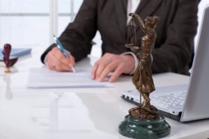 Criminal lawyer in office with lady justice statute on desk