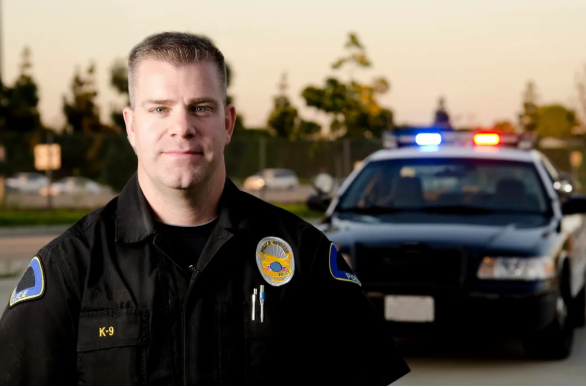 Police officer standing in front of a patrol car with flashing sirens during a DUI stop, highlighting the need for a Long Island DUI refusal lawyer