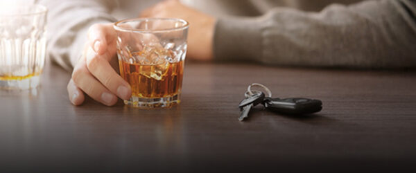 Man sitting at a bar with whiskey glass and car keys, suggesting potential Nassau County DUI consequences