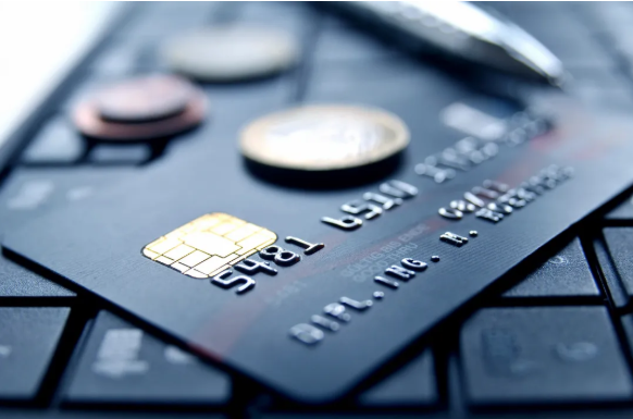 Credit card on computer keyboard with coins and pen symbolizing credit card fraud charges on Long Island